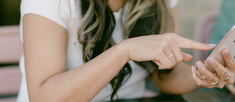 A close-up image of a person using a smartphone, symbolizing the effective use of nearshore IT services. The person's hand, adorned with rings, taps on the phone screen, representing communication and collaboration facilitated by Ascend's IT solutions. The image highlights the benefits of nearshore outsourcing, including proximity, cultural affinity, and cost-effectiveness, as part of Ascend's strategic approach to IT services for U.S. insurance firms.