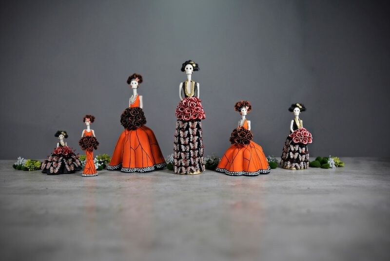 An arrangement of intricately crafted Catrina figurines, showcasing vibrant traditional attire. This image represents Ascend's initiative to support Mexican artists and manufacturers. Through platforms like The Catrina Shop and Mexico’s Finest, Ascend helps local talents gain global exposure, combining cultural celebration with the company's technological and logistical capabilities. This initiative is part of Ascend's broader mission to make a positive societal impact alongside its IT services.